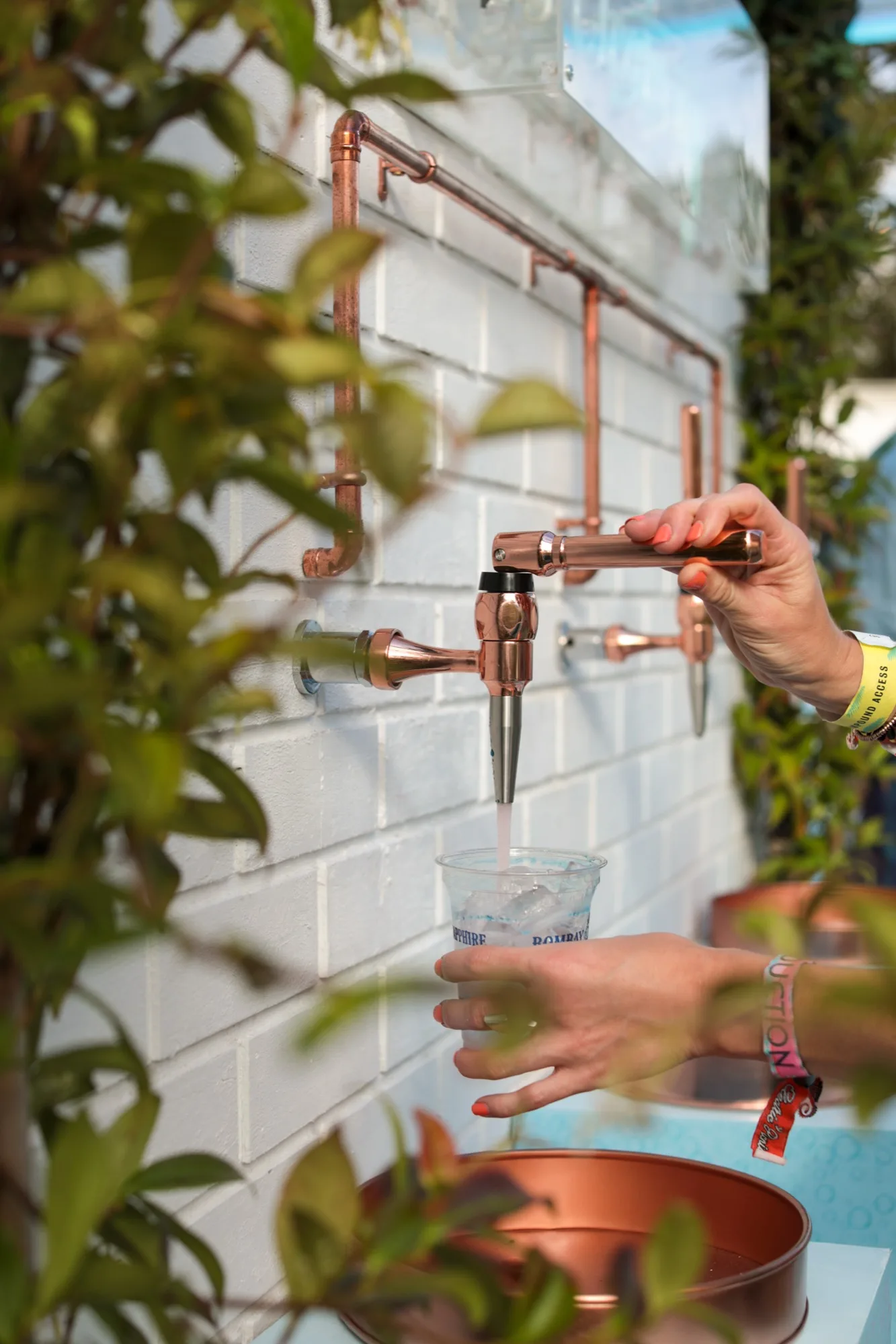 Guest pouring tonic from a bespoke copper tap wall