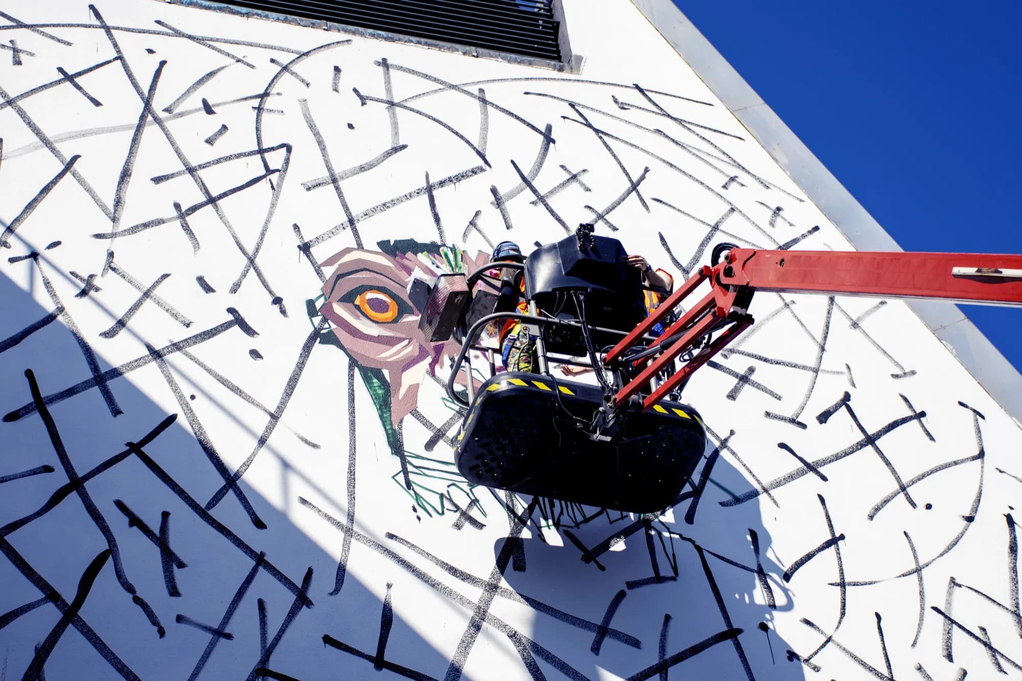 Arlin Graff painting the mural from a cherry-picker crane